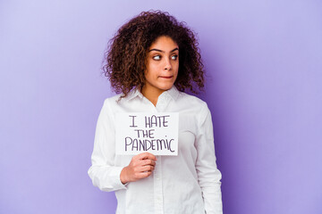 Young African American woman holding I hate pandemic placard isolated on purple background...
