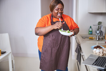 Excited Afro-American woman looking at tasty salad in bowl