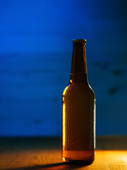 Cold beer bottle with water drops on wooden background, colored neon style