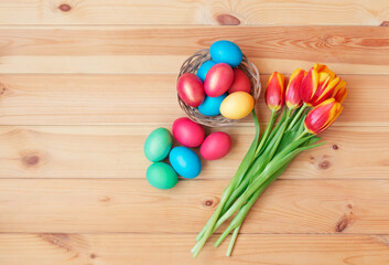 Obraz na płótnie Canvas Colorful Easter eggs and tulip flowers on wooden background.