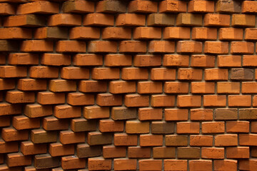 Brick wall with uneven geometric masonry. A wall of red bricks sticking out of the wall. Vertical format. Place for text