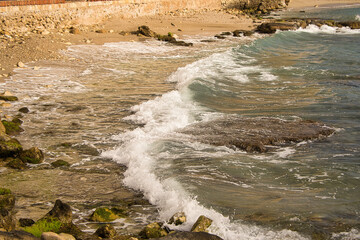 Sea waves lash line impact rock on the beach, located in Alicante