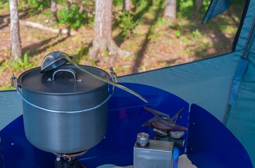 Camping bowler hat with a mitten and gas burner in a tourist tent