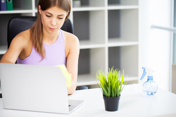 Woman cleaner tidies up the computer desk in the office.