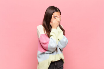 young pretty woman feeling scared or embarrassed, peeking or spying with eyes half-covered with...