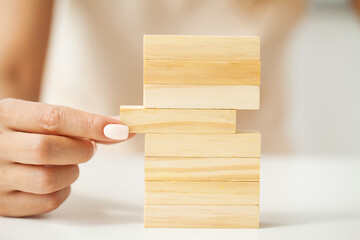 Woman hand putting and stacking blank wooden cubes on desk with copy space for input wording and infographic icon.