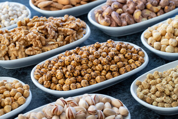 Roasted chickpeas in selective focus. Nuts on plate on a dark background. Walnut, Chickpeas, White Chickpeas, Dry mulberry, almond, cashew, pistachio. Types of nuts on the plate.