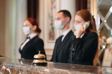 Check in hotel. receptionist at counter in hotel wearing medical masks as precaution against virus. Young woman on a business trip doing check-in at the hotel