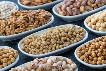 Dry Mulberry in selective focus. Nuts on plate on a dark background. Walnut, Chickpeas, White Chickpeas, Dry mulberry, almond, cashew, pistachio. Types of nuts on the plate.