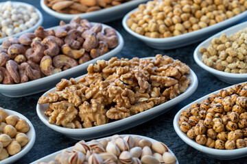 Walnut in selective focus. Nuts on plate on a dark background. Walnut, Chickpeas, White Chickpeas, Dry mulberry, almond, cashew, pistachio. Types of nuts on the plate.