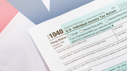 Closeup of US tax form 1040 on American flag.