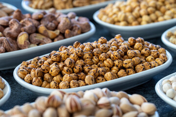 Roasted chickpeas in selective focus. Nuts on plate on a dark background. Walnut, Chickpeas, White Chickpeas, Dry mulberry, almond, cashew, pistachio. Types of nuts on the plate.