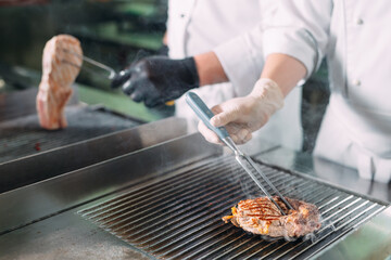 Cooks roast meat on the stove in the kitchen of a restaurant or hotel.