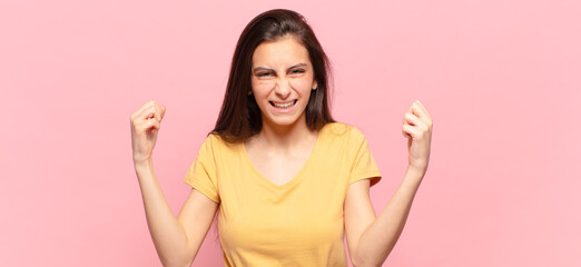 young pretty woman feeling happy, positive and successful, celebrating victory, achievements or...