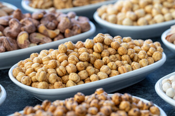Roasted chickpeas in selective focus. Nuts on plate on a dark background. Walnut, Chickpeas, White...
