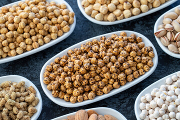 Roasted chickpeas in selective focus. Nuts on plate on a dark background. Walnut, Chickpeas, White Chickpeas, Dry mulberry, almond, cashew, pistachio. Types of nuts on the plate.