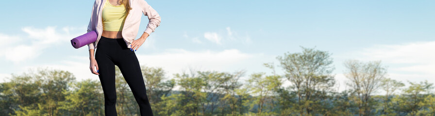 A young slim athletic girl in sportswear performs a set of exercises. Fitness and healthy lifestyle  against the background of forest.