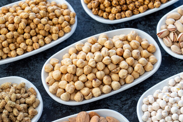 Hazelnuts in selective focus. Nuts on plate on a dark background. Walnut, Chickpeas, White Chickpeas, Dry mulberry, almond, cashew, pistachio. Types of nuts on the plate.