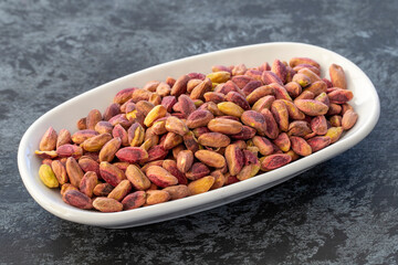 Pistachio kernels on plate on dark background