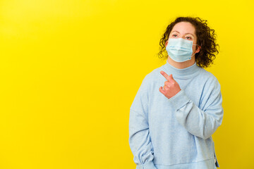 Young woman with Down syndrome wearing an antivirus mask isolated pointing to the side