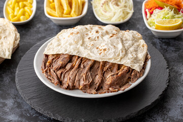Turkish kebab meat doner on wooden background. Served with doner lavash bread cooked on wood fire and with salad, onion and french fries.