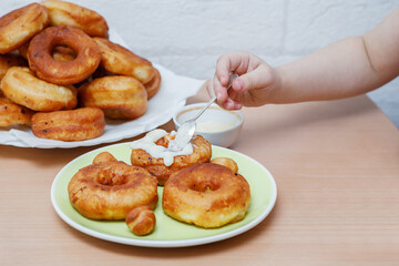 Traditional pastries. Homemade donuts. Photo 7: a child decorates ready-made fried donuts.