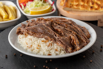 Meat on rice turns over on a dark ground. Turkish kebab doner