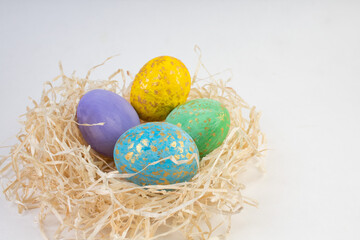 Fototapeta na wymiar Happy Easter card. Colorful shiny eggs in a nest isolated on a white background. Copy space for text.