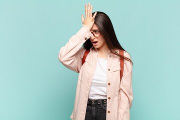 young pretty woman raising palm to forehead thinking oops, after making a stupid mistake or...