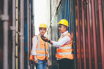 Asian container worker talking on walkie talkie to control work quality at dock. import export shipping business. freight cargo and logistic warehouse concept