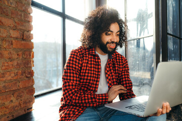 Young african american man with afro hairstyle works at the computer against the background of windows