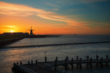 Fototapeta na wymiar Sunrise at the harbor in Vlissingen, the Netherlands. You can see the sea, breakwaters and beautiful colorful sky.