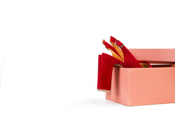Caja de cart&oacute;n rosa con unos zapatos rojos sobre un fondo blanco liso y aislado. Vista de frente. Copy space