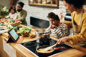 African American boy cooking with his mother in the kitchen.