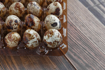 Group of quail eggs are put on clear tray on wooden table.