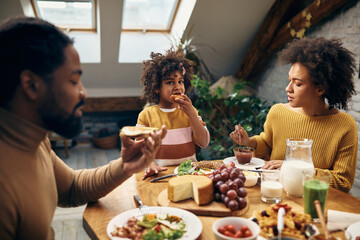 African American family eating breakfast at dining table at home.