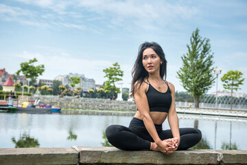 Fototapeta na wymiar Young slim woman in sportswear practicing yoga near lake, nature. Healthy lifestyle
