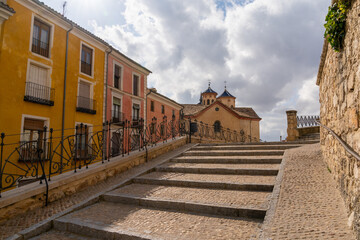cobblestone stairs leading into the heart of the old city center of Cuenca witl El Salvador church in the background