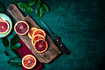  Red orange cut into slices on a wooden cutting board top view, free space for text