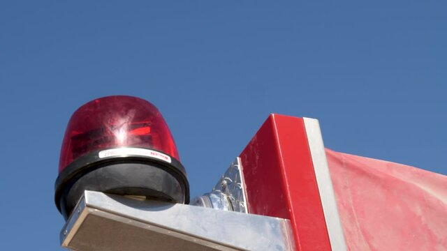 Closeup Looking up at rotating emergency light atop a red fire engine against a clear blue sky