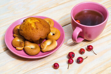 Homemade round bagels with muffins in a purple plate and rosehip tea. Idea for a delicious breakfast or dinner. Top view