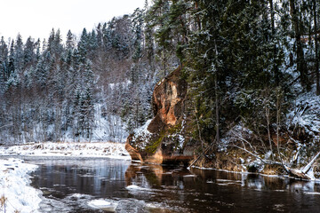 Fototapeta na wymiar Zvartas red rock and river Amata at city Cesis in Latvia. Winter photo