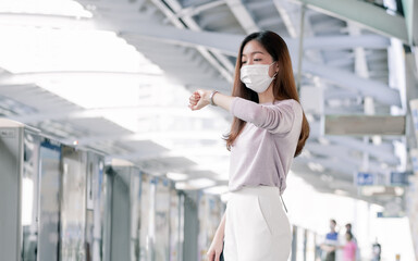 Woman wearing face mask and waiting for a train while standing on railway station