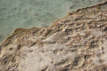 Calcium carbonate mineral deposits background. Close up of travertine pool with clear hot water. Pamukkale, Turkey.