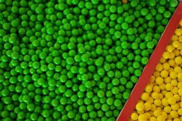 Dragees in the colored glaze close up. Green and yellow candies background. Junk food concept.