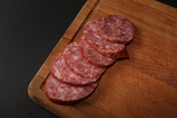 Salami sausage cut into slices on a stick isolated on a black background