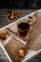 A cup of tea on a white tray, dried flowers, warm background
