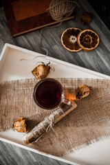 A cup of tea on a white tray, dried flowers, warm background