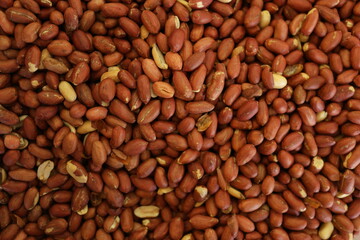 Pile of peanuts with skin close up. Peeled peanuts background.