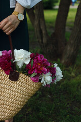 bouquet of peonies in a bag of a young woman on a blurred background of the park. photo details. macro photo